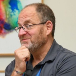 Profile picture of a man wearing glasses with his hand on his chin. 