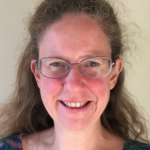 Person wearing glasses smiling at the camera.